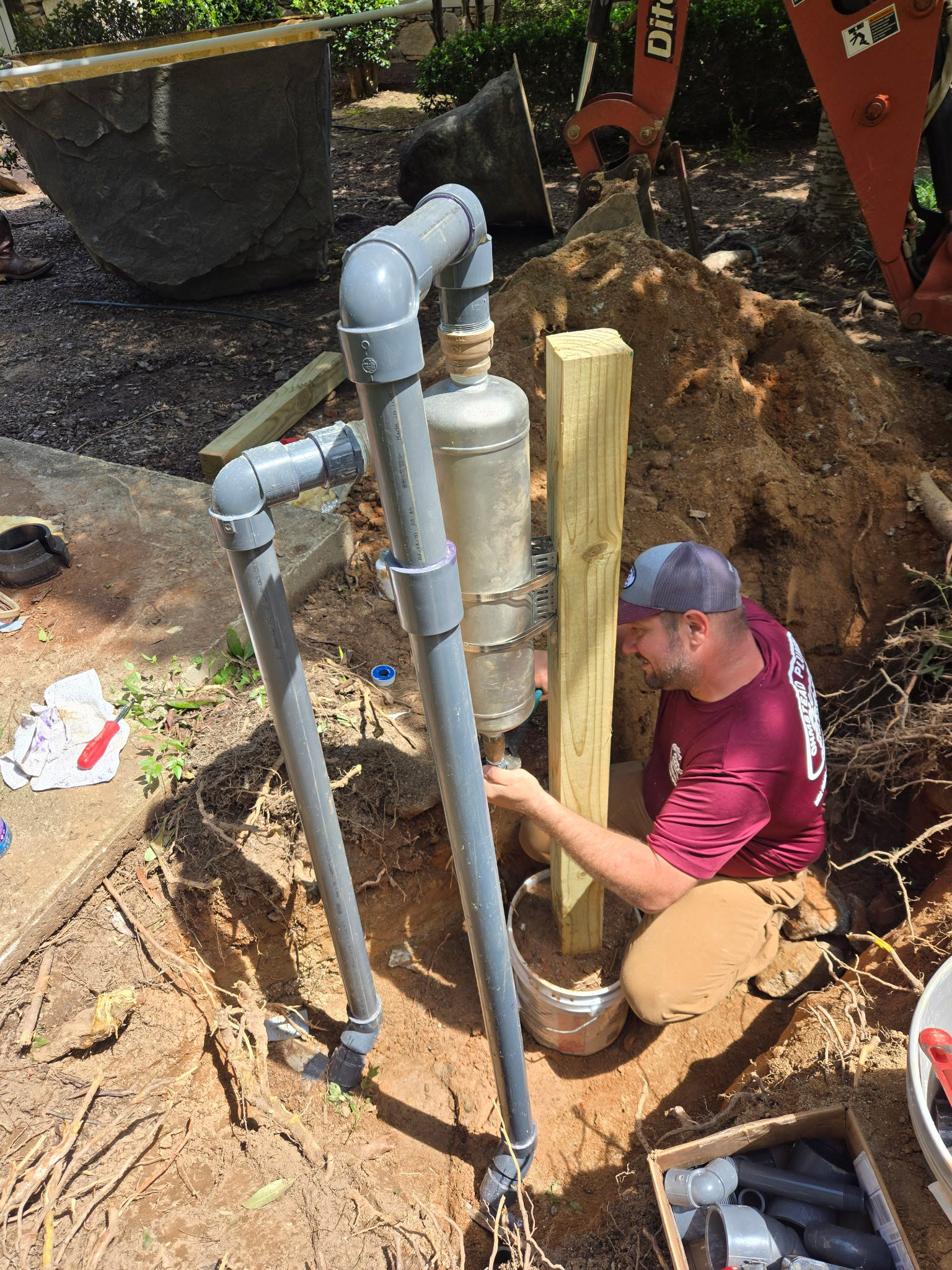 commercial-water-treatment-installation-rutherford-county-nc Ohmstead Plumbing technician installing a commercial water treatment and filtration system in Rutherford County, North Carolina with underground piping and professional-grade water purification equipment for local foothills properties.